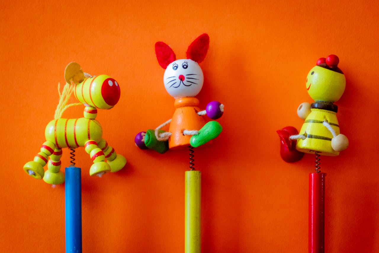 The Art of Drawing Readers In: Your attractive post title goes here Close-up of three colorful wooden toys on a vibrant orange background, perfect for children's themes.